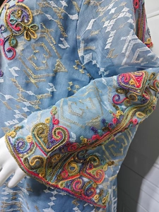 Gros plan de broderies complexes et de paillettes colorées sur une robe bleu clair