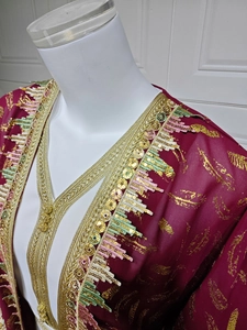 Détail d'un caftan en mousseline bordeaux avec imprimé doré et broderie de sequins