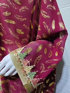 Détail de l'abaya en mousseline bordeaux avec imprimé plume dorée et franges à paillettes