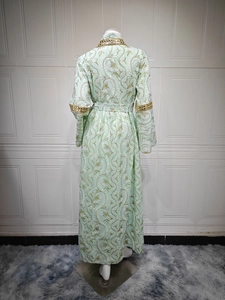 Dettaglio del vestito lungo verde menta con ricami floreali bianchi e paillette dorate