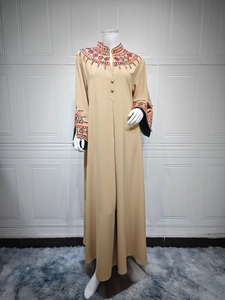 Detailed close-up of colorful floral embroidery and gold buttons on a beige maxi dress