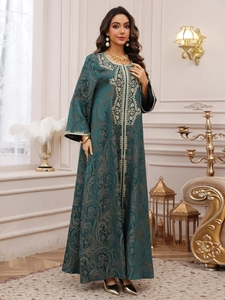Close-up of golden embroidery and paisley pattern on dark green evening kaftan gown