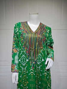 Détail de robe de soirée verte avec broderies blanches et paillettes métalliques