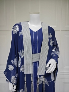 Détails de broderie florale pailletée argentée et pompons sur l'abaya bleu marine