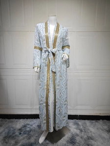 Dettaglio di un kaftan azzurro ricamato con pizzo dorato e motivi floreali eleganti