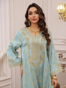 Détail d'une robe caftan bleu clair avec broderies dorées et bijoux ethniques en or