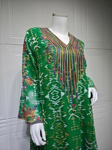 Détail d'une robe en tulle vert avec broderies, paillettes en V et élégants glands