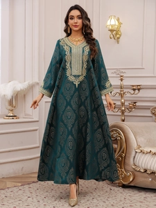 Détail macro d'une robe caftan vert émeraude avec jacquard doré et broderie de luxe