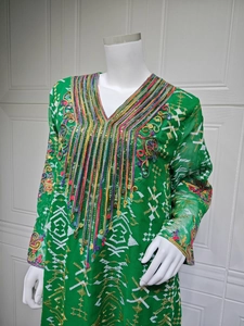 Détail du col en V de la robe verte avec sequins colorés et broderies florales raffinées