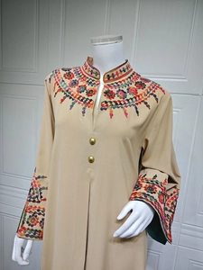 Detail of colorful hand-beaded floral embroidery and golden buttons on beige dress