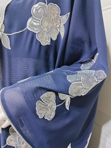 Détail de broderie florale en sequins argentés sur tissu georgette bleu foncé pour robe