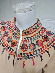 Detailed close-up of colorful floral embroidery on khaki mandarin collar dress