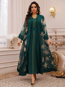Detailed embroidery of golden palm leaves on a dark green sheer robe and dress set