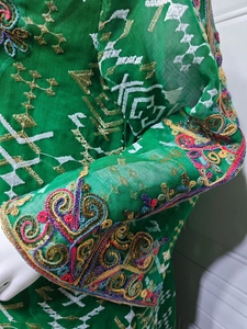 Gros plan détaillé de la broderie ethnique et des paillettes colorées sur les manches vertes