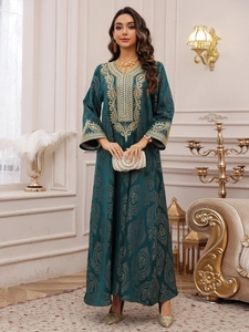 Détails de broderie dorée sur une robe kaftan vert foncé avec des motifs floraux