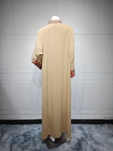Detailed view of ethnic embroidery on the collar and cuffs of a beige maxi dress