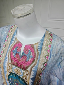 Détail de broderie complexe et paillettes sur le décolleté d'une tunique ethnique