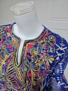 Close-up of ethnic floral embroidery and gold sequins on dark blue mesh dress neckline