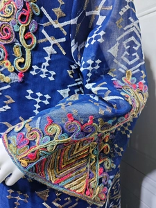 Detail of blue mesh maxi dress featuring intricate ethnic embroidery and gold sequins