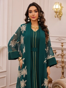 Detail of dark green two-piece maxi dress featuring golden palm embroidery and mesh cardigan