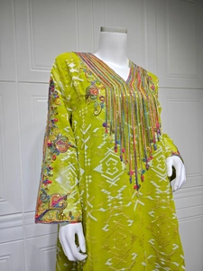 Gros plan de broderies colorées, de paillettes et de franges perlées sur une robe verte