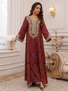 Détail d'un caftan bordeaux avec broderies dorées et motifs cachemire