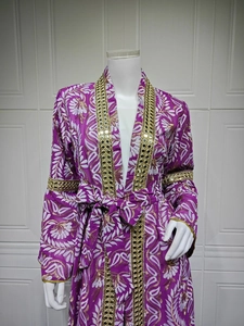 Dettaglio macro di vestito viola con ricami in paillettes d'oro e motivi floreali