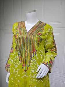 Détail de la robe vert citron avec broderies ethniques, sequins et glands à franges