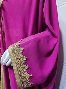 Detail view of red Abaya dress featuring gold lace embroidery and sequin cuffs