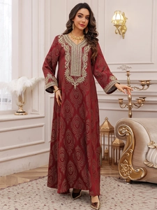 Détails de la broderie dorée et du motif jacquard sur une robe caftan de luxe rouge