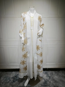 Detail of white abaya featuring gold palm tree embroidery and matching belted waist