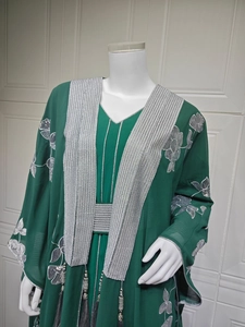 Détail de la broderie de paillettes argentées et des pompons sur la robe Abaya verte