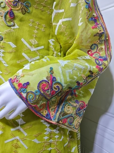 Détail de robe en mesh vert citron avec broderies florales et poignets à paillettes