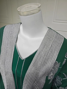 Détails de broderie argentée sur le col en V d'une robe caftan longue vert foncé