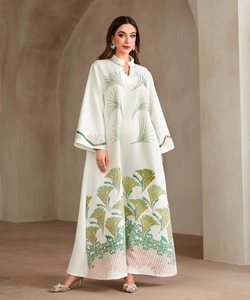 Detail of elegant white embroidered abaya featuring green and pink floral patterns