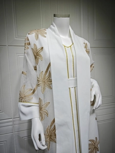 Detailed close-up of intricate gold floral embroidery on a white fashion maxi cardigan dress