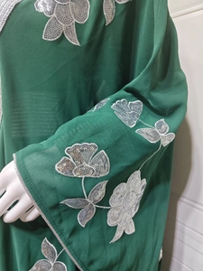 Détail de la robe en mousseline vert foncé avec broderies florales de paillettes argentées