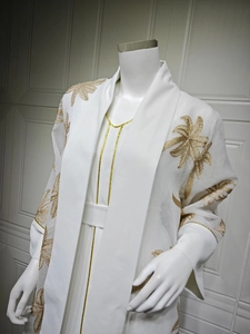 Close-up of golden palm leaf embroidery and sequin detail on white abaya cardigan
