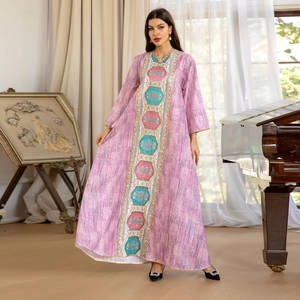 Robe caftan rose à manches longues avec broderie ethnique centrale dans un cadre chaleureux