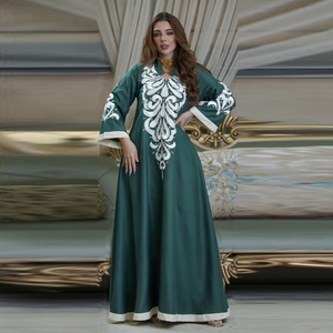 Dark green embroidered kaftan dress with white scrolls and long sleeves in luxury setting