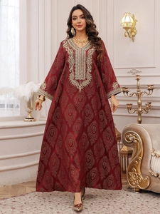 Détails macro de la robe caftan rouge foncé avec broderie florale dorée de luxe