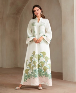Detail of elegant ivory maxi dress featuring green floral motifs and flared sleeves