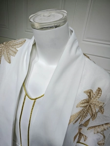 Detail of white robe with intricate gold leaf embroidery and metallic piping on the collar