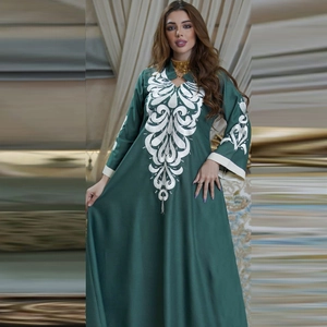 Detail of white embroidery patterns on a dark green long-sleeved ethnic kaftan dress