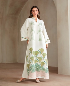 Detail of white jacquard abaya with green feather embroidery and beaded V-neckline