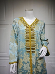 Detailed view of golden embroidery and beadwork on light blue jacquard kaftan dress
