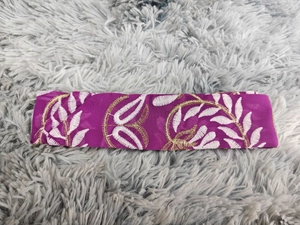 Dettaglio di una fascia in seta viola con ricami floreali in bianco e oro di alta qualità