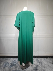 Détail de l'abaya vert foncé avec broderie, sequins et motifs dorés à pompons
