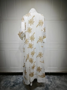 Detail of white long cardigan featuring gold palm tree embroidery and delicate piping