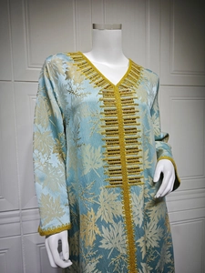 Close-up of golden floral embroidery and intricate beadwork on light blue satin dress